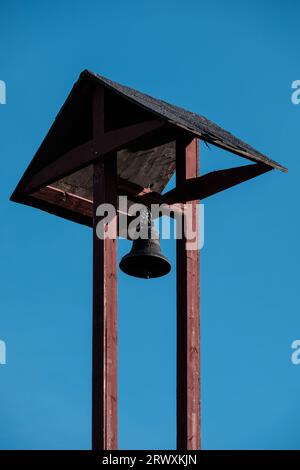 Helsinki / Finlande - 18 SEPTEMBRE 2023 : gros plan d'un vieux poteau en bois avec une cloche contre un ciel bleu vif Banque D'Images