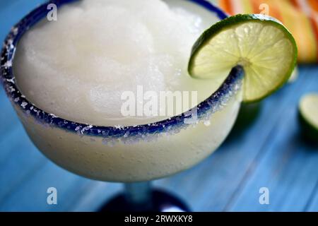 margarita congelée dans un verre bleu salé à bordure avec une tranche de citron vert Banque D'Images