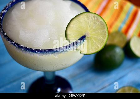 margarita congelée dans un verre bleu salé à bordure avec une tranche de citron vert Banque D'Images