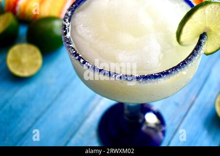 margarita congelée dans un verre bleu salé à bordure avec une tranche de citron vert Banque D'Images