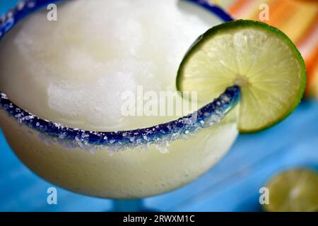 margarita congelée dans un verre bleu salé à bordure avec une tranche de citron vert Banque D'Images