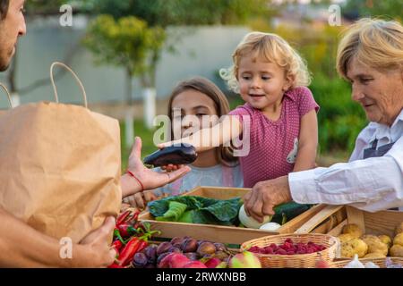 Grand-mère et petite-fille vendent des légumes et des fruits au marché fermier. Mise au point sélective. alimentation. Banque D'Images