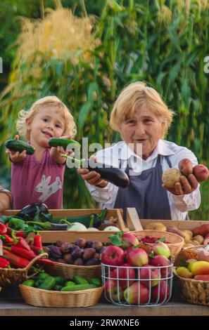 Grand-mère et petite-fille vendent des légumes et des fruits au marché fermier. Mise au point sélective. alimentation. Banque D'Images