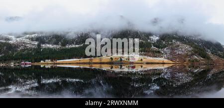 Automne dans les montagnes norvégiennes. Panorama d'un lac transparent bleu reflétant des montagnes couvertes de forêt d'épinettes de conifères à feuilles persistantes, une fa de montagne Banque D'Images
