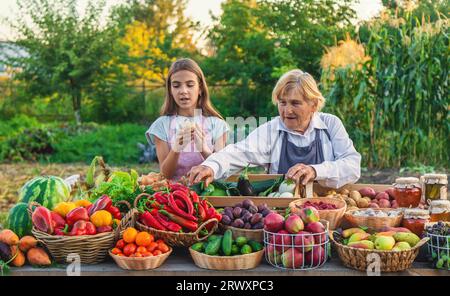 Grand-mère et petite-fille vendent des légumes et des fruits au marché fermier. Mise au point sélective. alimentation. Banque D'Images