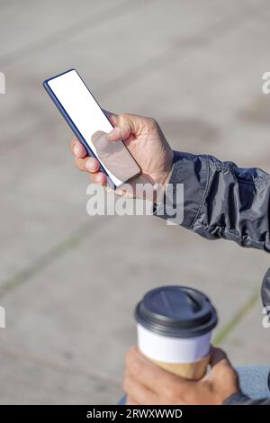 Détail des mains d'un homme latin tenant un téléphone portable avec un écran vide. Banque D'Images