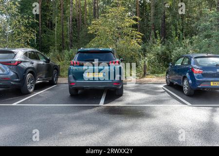 Parking inconsidéré, voiture garée sur la ligne prenant deux places de parking, Royaume-Uni Banque D'Images