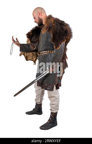 Viking médiéval avec une épée dans une peau d'ours, examine la décoration sous la forme d'une dent d'ours. Isolé sur blanc Banque D'Images