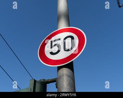 panneau de limite de vitesse de 50 kmh sur un poteau. Le panneau de signalisation interdit aux automobilistes d'aller plus vite que cinquante kilomètres par heure. Le symbole est utilisé dans les villes. Banque D'Images