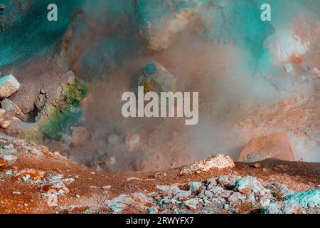 Vue en gros plan au parc national de Yellowstone montre des couleurs volcaniques spectaculaires de sédiments en rouge, vert et bleu. La vapeur s'élève de la piscine boueuse d'eau. Banque D'Images