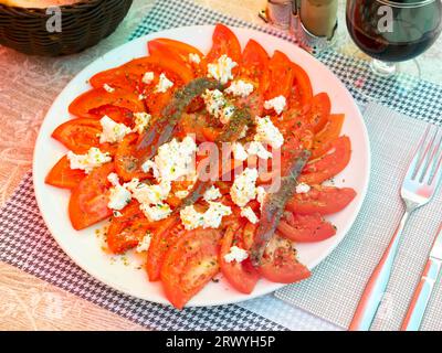 Savoureuses tranches de tomates avec du fromage et des anchois. Banque D'Images