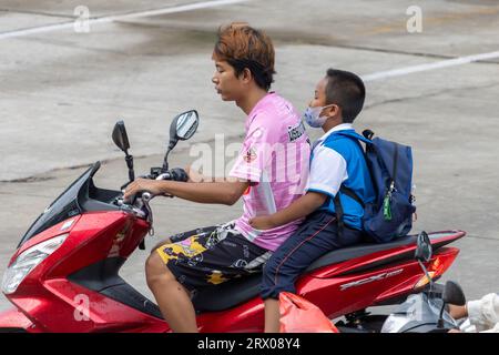 SAMUT PRAKAN, THAÏLANDE, JUIN 06 2023, Un homme conduit une moto avec un garçon avec un sac à dos Banque D'Images