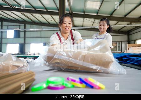 Comté de Luannan, Chine - 30 août 2022 : travailleurs travaillant nerveusement sur la chaîne de production d'emballages de pelle en acier. Banque D'Images