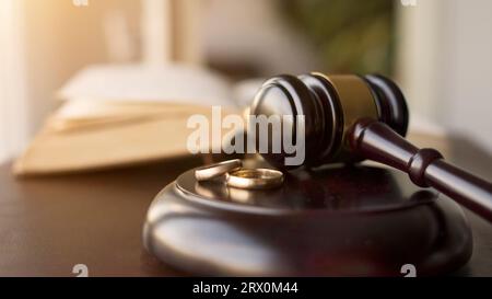 Marteau de juge et anneaux de mariage pour la procédure de divorce. Maillet d'un juge statuant sur l'affaire de divorce de mariage et la garde. Mise au point sélective sur les anneaux. Banque D'Images