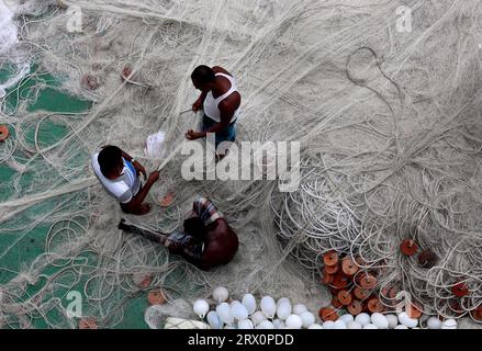 20 septembre 2023, Chittagong, rivière Karnaphuli, Bangladesh : pêcheurs occupés à réparer des filets pour aller pêcher en mer assis sur la drague de sable dans la rivière Karnaphuli de Chittagong, Bangladesh. (Image de crédit : © Mohammed Shajahan/ZUMA Press Wire) USAGE ÉDITORIAL SEULEMENT! Non destiné à UN USAGE commercial ! Banque D'Images