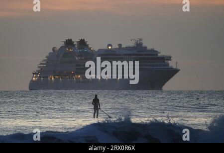 Un paddleboarder au large de Tynemouth Longsands alors que le navire de croisière Seabourn Ovation arrive à l'embouchure de la Tyne. Date de la photo : Vendredi 22 septembre 2023. Banque D'Images