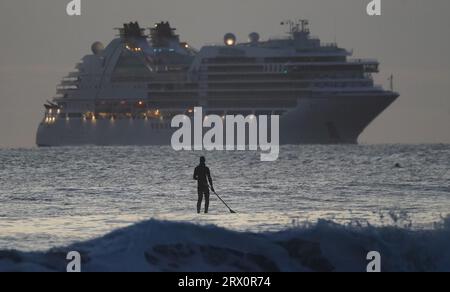 Un paddleboarder au large de Tynemouth Longsands alors que le navire de croisière Seabourn Ovation arrive à l'embouchure de la Tyne. Date de la photo : Vendredi 22 septembre 2023. Banque D'Images