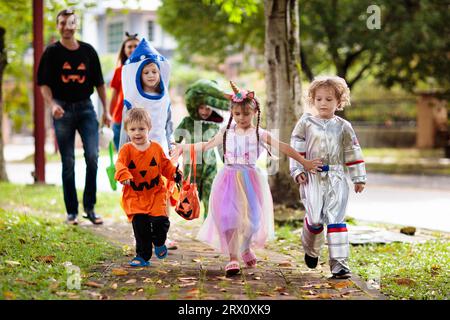 Enfant en costume d'Halloween. Race mixte asiatique et caucasien enfants et parents de trick ou de plaisir dans la rue. Petit garçon et fille avec lanterne de citrouille Banque D'Images