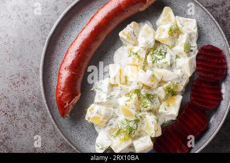 Saucisse de lard suédois Isterband avec pommes de terre en sauce crème avec aneth et betteraves bouillies gros plan sur une assiette sur la table. Vue de dessus horizontale depuis abov Banque D'Images