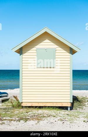 Vue frontale de l'arrière d'une cabane en bois jaune sur la plage de Skanör med Falsterbo à la Öresund au soleil du matin, Skåne, Suède Banque D'Images