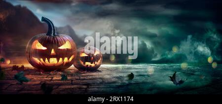 Citrouilles d'Halloween dans Une nuit effrayante avec des effets de lumière et de fumée abstraits défocalisés Banque D'Images