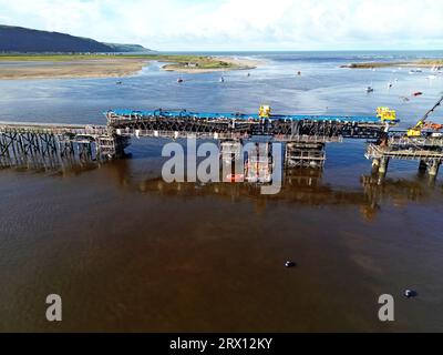 Barmouth, Royaume-Uni, 21 septembre 2023. Les travaux se sont poursuivis pour enlever les anciennes sections du pont ferroviaire de Barmouth hier après que le mauvais temps ait reporté les travaux de 3 jours. L'emblématique structure classée Grade II*, vieille de 157 ans, sur l'estuaire de Mawddach, en est aux dernières étapes d'un projet de reconstruction de 30 millions de livres sterling sur 3 ans. Les deux travées en acier sont remplacées par de nouvelles structures identiques, utilisées temporairement pour maintenir les grues qui abaissent les sections de l'ancien pont corrodé sur des pontons en dessous et enlevées pour élimination. Le chemin de fer reste fermé jusqu'en décembre. G.P. Essex/Alamy Live News Banque D'Images