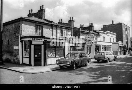 Photographie en noir et blanc d'archives de 1975 de magasins à l'angle de Crownstone Road et Brixton Water Lane à Lambeth, au sud de Londres. Depuis démoli. Banque D'Images