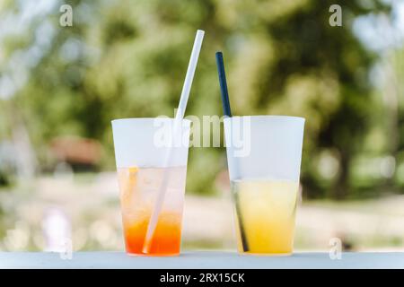 Deux verres avec différents cocktails rafraîchissants d'été sur la table d'un café d'été dans le parc. Seringue Aperol et limonades Banque D'Images