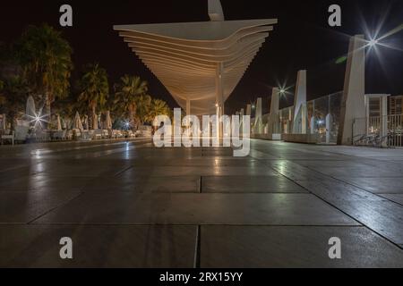 Promenade publique à Malaga, Parmeral de las Sorpresas à la fin de la nuit dans les couleurs des lumières nocturnes de la ville. Architecture urbaine moderne, Malaga. Banque D'Images