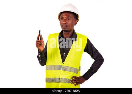 un ingénieur en construction avec casque de sécurité debout sur fond blanc tenant le téléphone portable avec l'air triste. Banque D'Images