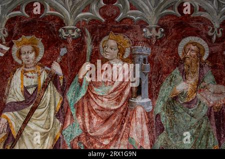 Martyrs chrétiens, Sainte Catherine d'Alexandrie et Sainte Barbara, avec Jean-Baptiste. Fresque gothique tardive dans la Franziskanerkirche (église franciscaine) à Lienz, Tyrol oriental, Autriche. L'un des deux anciens retables peints vers 1440 par Nikolaus Kenntner, un artiste de Lienz. Banque D'Images