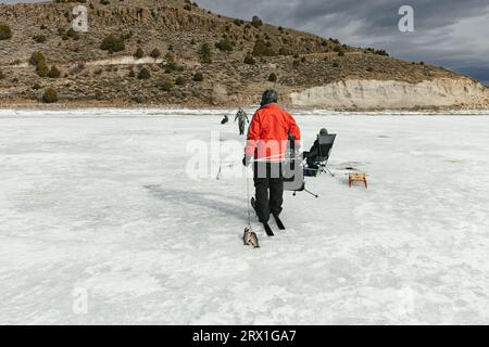 Famille sur le lac gelé dans les montagnes pêche sur glace et skis de fond Banque D'Images
