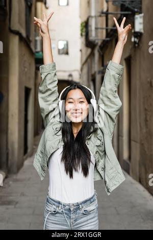 Gros plan d'une jeune femme prospère levant les bras dans la rue. Banque D'Images