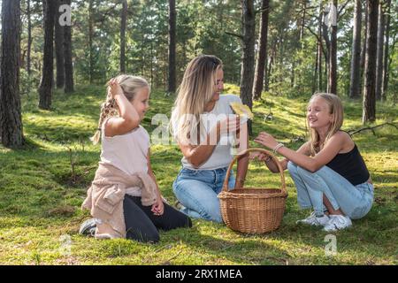 Femme blonde avec deux filles, 7 et 10 ans, à la recherche de champignons dans la forêt à Ystad, Scania, Suède, Scandinavie Banque D'Images