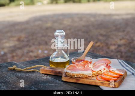 Toast à la tomate, à l'huile d'olive et au jambon ibérique, cuisine typiquement espagnole, sur une table en bois à la campagne Banque D'Images