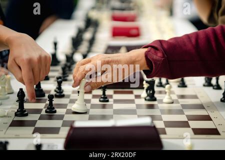 Jouer aux échecs, mains de l'enfant et du senior, Kid Boy Moving Pawn Piece, Man Thinking échiquier. un enfant apprend à un vieil homme à jouer aux échecs. vieux et jeune pla Banque D'Images