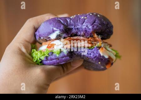 photo rapprochée de tenir un hamburger violet maison avec une bouchée Banque D'Images