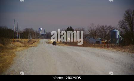 Un homme Amish dans un buggy tiré par des chevaux roule librement sur une route de gravier vers Bloomfield dans le comté de Davis, Iowa. Banque D'Images