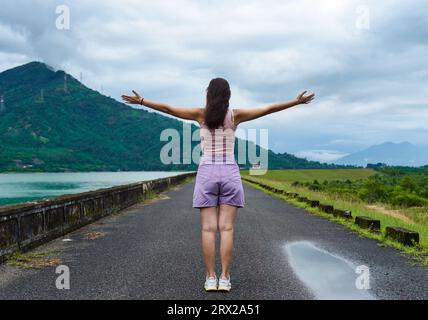 Jeune femme russe voyageur avec les bras ouverts près du lac et des montagnes dans la province de Khanh Hoa, Vietnam Banque D'Images