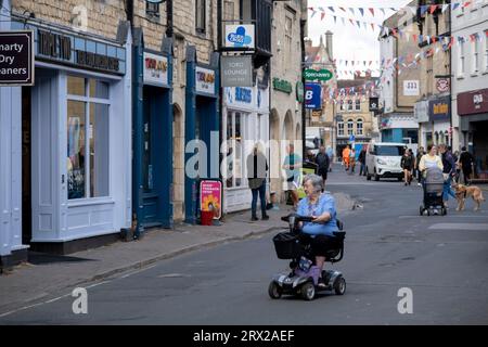 Lady sur son scooter de mobilité sur Dyer Street le 13 septembre 2023 à Cirencester, Royaume-Uni. Cirencester est une ville de marché dans le Gloucestershire. C'est la huitième plus grande colonie du Gloucestershire et la plus grande ville des Cotswolds. La rue principale est le centre de nombreuses villes anglaises, et traditionnellement où les gens peuvent trouver des biens de tous les jours. Magasins de détail, épiceries, marques et entreprises locales, ainsi que des banques, des cafés et des restaurants. Banque D'Images