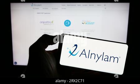 Personne tenant le téléphone portable avec le logo de la société américaine Alnylam Pharmaceuticals Inc. Sur l'écran devant la page Web de l'entreprise. Concentrez-vous sur l'affichage du téléphone. Banque D'Images