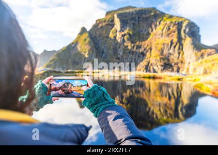 Perspective personnelle de femme photographiant des montagnes en automne avec smartphone, A i Lofoten, Moskenes, îles Lofoten, Nordland, Norvège, Scandinavie Banque D'Images