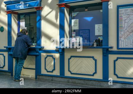 Femme achetant des billets de train ou faisant une demande à la billetterie de la gare de King's Lynn. Banque D'Images