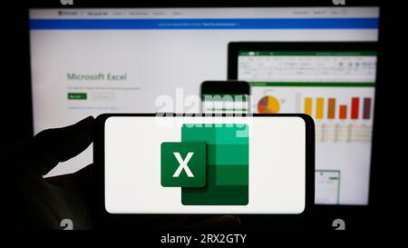 Personne tenant le smartphone avec le logo de l'éditeur de feuille de calcul Microsoft Excel sur l'écran en face du site Web. Concentrez-vous sur l'affichage du téléphone. Banque D'Images