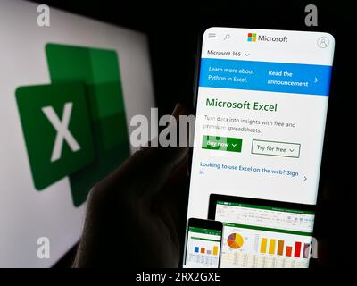 Personne tenant le téléphone portable avec le site Web de l'éditeur de tableur Microsoft Excel sur l'écran en face du logo. Concentrez-vous sur le centre de l'écran du téléphone. Banque D'Images