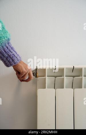 Femme ajustant la température sur le radiateur de chauffage. Inflation des prix de l'électricité et du gaz. Banque D'Images