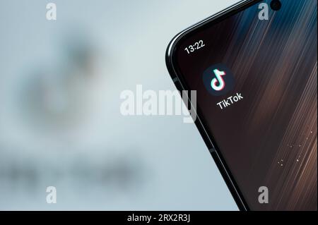 New York, États-Unis - 21 août 2023 : utilisation de l'application TikTok sur l'écran du smartphone gros plan avec un arrière-plan de logo flou Banque D'Images