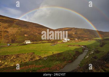 Un arc-en-ciel de vallée se forme face à un bourdonnement automnal, à Duckpool, une anse éloignée près de Bude, côte nord de Cornouailles, Angleterre, Royaume-Uni, Europe Banque D'Images