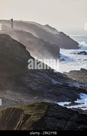 Falaises atlantiques pilonnées par les vagues dans un temps hivernal orageux, à Pendeen, avec les ruines d'anciennes mines d'étain Banque D'Images