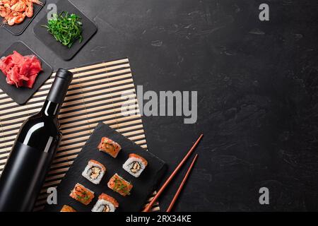 Ensemble de sushi et maki avec une bouteille de vin à table en pierre. Vue de dessus avec l'exemplaire de l'espace. Banque D'Images